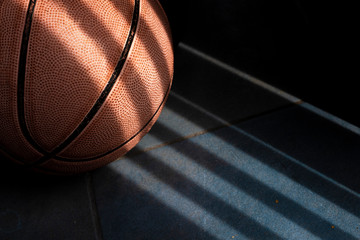 An orange basketball ball on a dark blue floor. Shadow drawing.