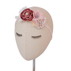 A head mannequin wearing bouquet of flowers made out of fabric cloth textile in beautiful soft pastel colors that can be used as hair accessory, decoration, and embellishment