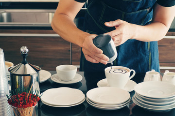 Barista making hot latte art at coffee shop for serving customer. Barista working lifestyle and drink preparation at cafe concept