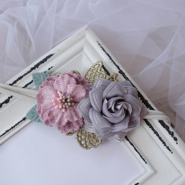 Bouquet of flowers made out of fabric cloth textile in beautiful soft pastel pink and gray colors placed on vintage photo frame that can be used as hair accessory, decoration, and embellishment
