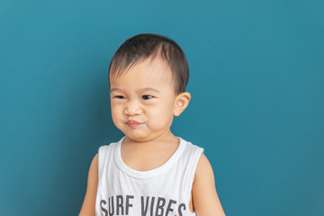 Asian little boy makes a cheeky face on blue background,Happy childhood.