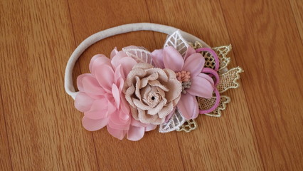 Bouquet of flowers made out of fabric cloth textile in beautiful soft pastel pink theme colors placed on wood texture table that can be used as hair accessory, decoration, and embellishment