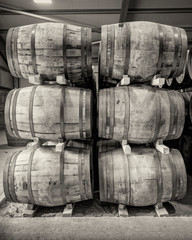 Stacks of traditional full whisky barrels, set down to mature, in a large warehouse