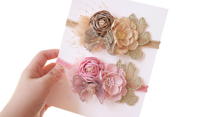 A hand holding bouquet of flowers made out of fabric cloth textile in beautiful soft pastel pink and brown theme colors that can be used as hair accessory, decoration, and embellishment