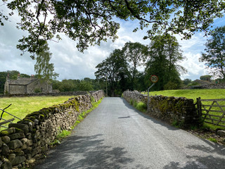 Country lane, leading into a village, with moss covered dry stone walls, and fields nearby in, Kirby Malham, Skipton, UK