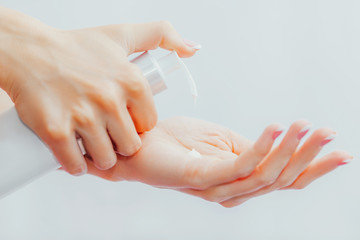 Naklejka premium Woman applies cream to her hands from dispenser