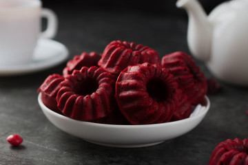 red cupcakes with stripes on a white plate. Tea party with cupcakes on a plate with a white mug and a teapot