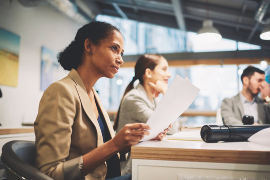 Professional Afro American Female Manager Dressed In Formal Outfit Preparing To Make Report During Conference Meeting With Company Leaders Rereading Text And Documentation Sitting In Good Mood