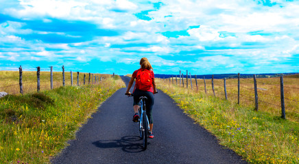 woman biking ion the road on countryside