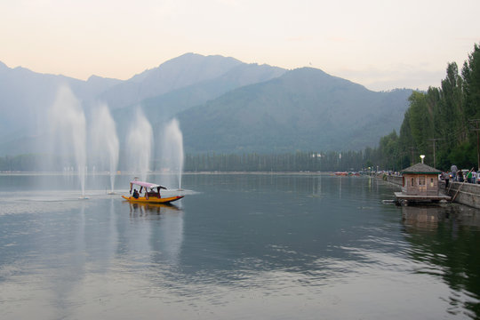 Fountains over the Dal Lake with mountains in the background, at dusk. Dal Lake is the most famous lakes of Jammu and Kashmir, India and is tourist attraction from all over the world.