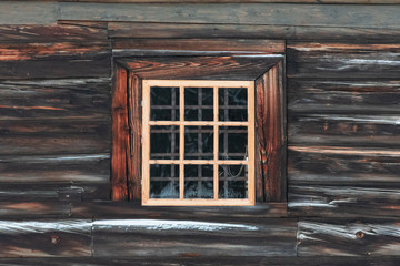 A window in an old wooden building made of boards covered with snow