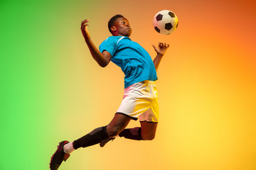 High jumping. Male soccer, football player training in action isolated on gradient studio...