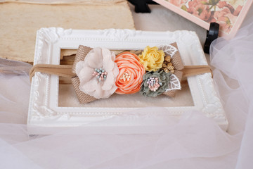 Fototapeta na wymiar Handmade flower made out of fabric cloth textile in beautiful soft pastel colors placed on white photo frame that can be used as hair accessory, decoration, and embellishment