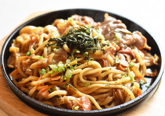 Close-up view, Fried yakisoba with tomato sauce with kurobuta pork on a black round plate.