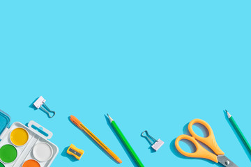 Back to school. Stationery: scissors, pens, pencils, paper clips, watercolor paints. The concept of learning, children's creativity. Blue background, top view, flat lay, copy space.