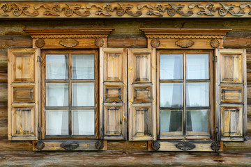 Two wooden windows with shutters on wall of old village house close-up