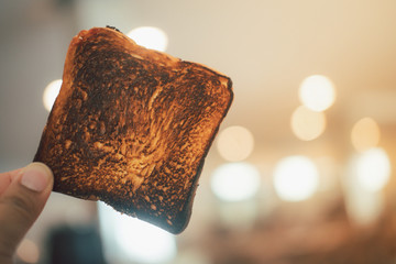 Man holding burnt toast bread slice