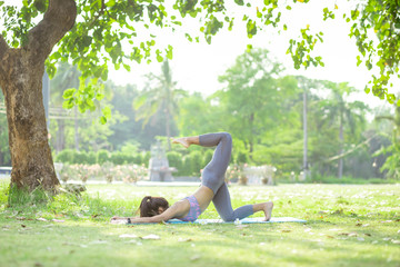 Young asian woman doing yoga under the tree in park