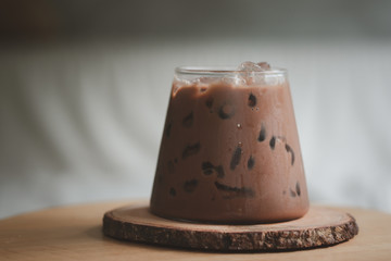 A glass of iced Mocha put on wood saucer