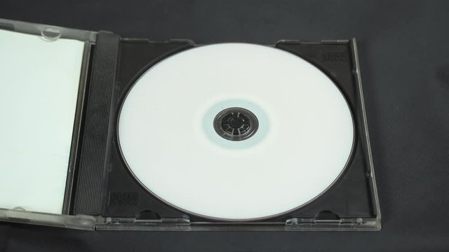 Hand picks up and installs a white CD DVD disc in a plastic box.