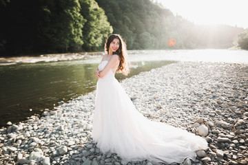Portrait of stunning bride with long hair standing by the river