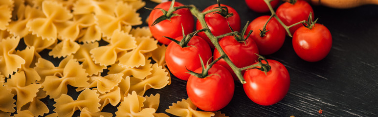 raw Italian farfalle with tomatoes on black background, panoramic shot