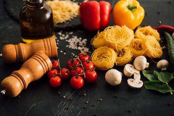 raw Italian Capellini with vegetables on black background