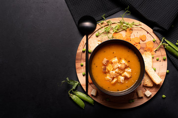 carrot and green pea puree soup in a black bowl