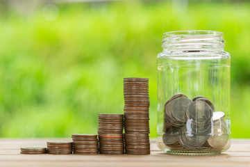 Coin Stack , coin in Glass bottle  in green bokeh background. Save Coin in Jar isolated on white or gray background. Business concept