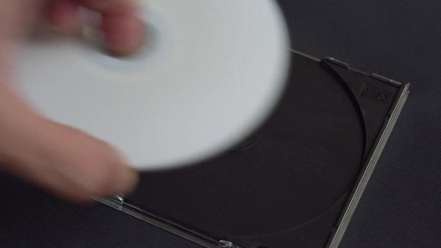 Hand picks up and installs a white CD DVD disc in a plastic box. the disk is labeled data.