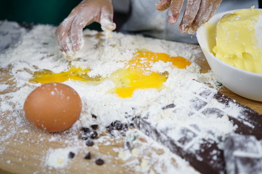 Close up Hand playing with flour eggs, kids cute girl having fun making cake, messy kitchen.