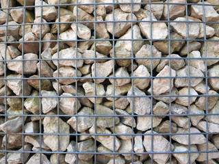 grande quantit&agrave; di sassi dietro una rete metallica