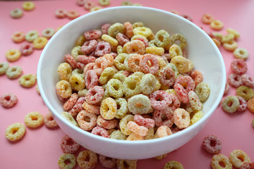 colorful ring corn flakes in a bowl on pink background 