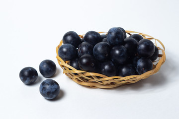 Plum in a wicker basket. Photo on a white background. Summer harvest
