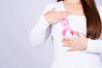 Breast cancer awareness ribbon on woman chest and doing self exam on grey background. Medical, healthcare for advertising concept.