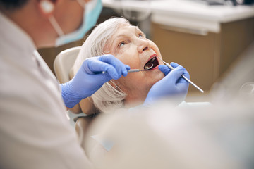Elderly female having her teeth examining in the orthodontist