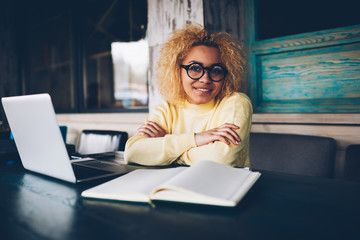 Portrait of prosperous female copywriter satisfied with occupation working remotely in cafe...