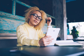 Beautiful African American female blogger checking comments from followers under new publication on...
