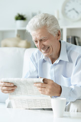 Fototapeta na wymiar Portrait of senior man reading newspaper at home
