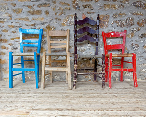 Fototapeta na wymiar four vintage chairs on natural wood floor against a rough stonewall