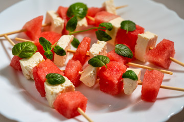 watermelon canapes with cheese sprinkled with mint on a plate