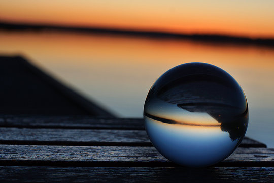 A transparent glass ball flips the pier and the sunset on the lake