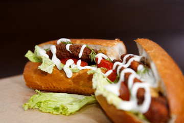 Sandwich with cutlet lies on a pacifier covered with kraft paper, and the side of the sauce to it