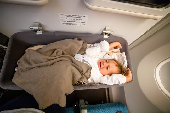 Infant Passenger Toddler Wakes Up On The Airplane And Stretches In Special Baby Bassinet