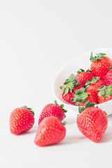Close up, vertical shot, fresh strawberries ready to eat in a white bowl on a white background. Selective focus, concepts, copy space