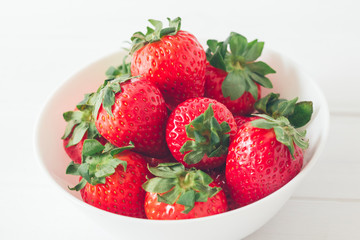 Close up, horizontal shot, fresh strawberries ready to eat in a white bowl on a white background. Selective focus, concepts