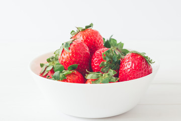 Close up, horizontal shot, fresh strawberries ready to eat in a white bowl on a white background. Selective focus, concepts