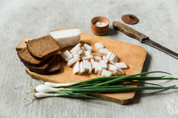 lard,bacon with black bread and green onions with salt on the wooden board. grey background. Ukrainian traditional appetizer