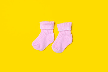 Pink baby socks on yellow background isolation, top view