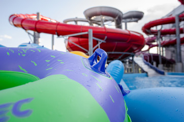close-up of tubing for riding from a water slide against the background of colorful plastic slides in a water park under sunlight